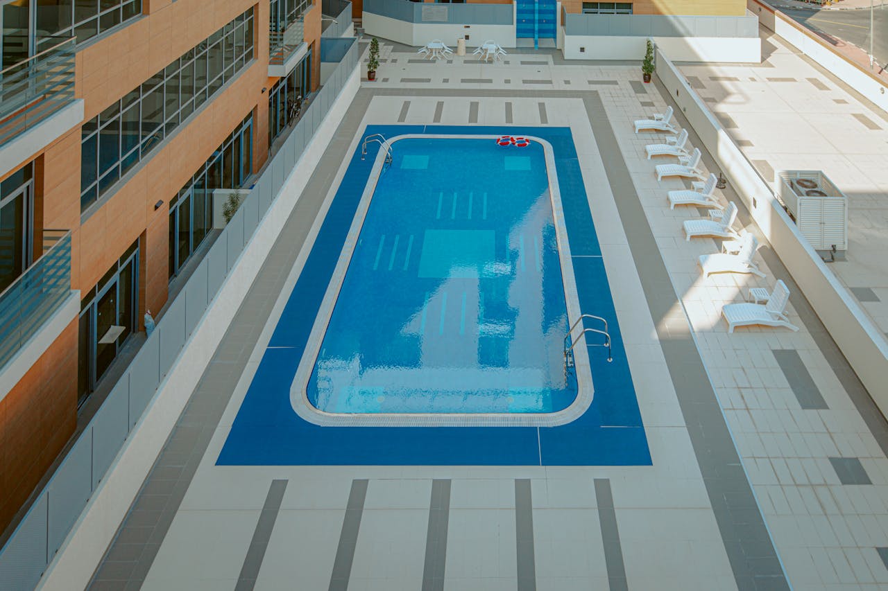 Mastering the First Impression: Your intriguing post title goes here High-angle view of a modern apartment complex rooftop pool with sunloungers.